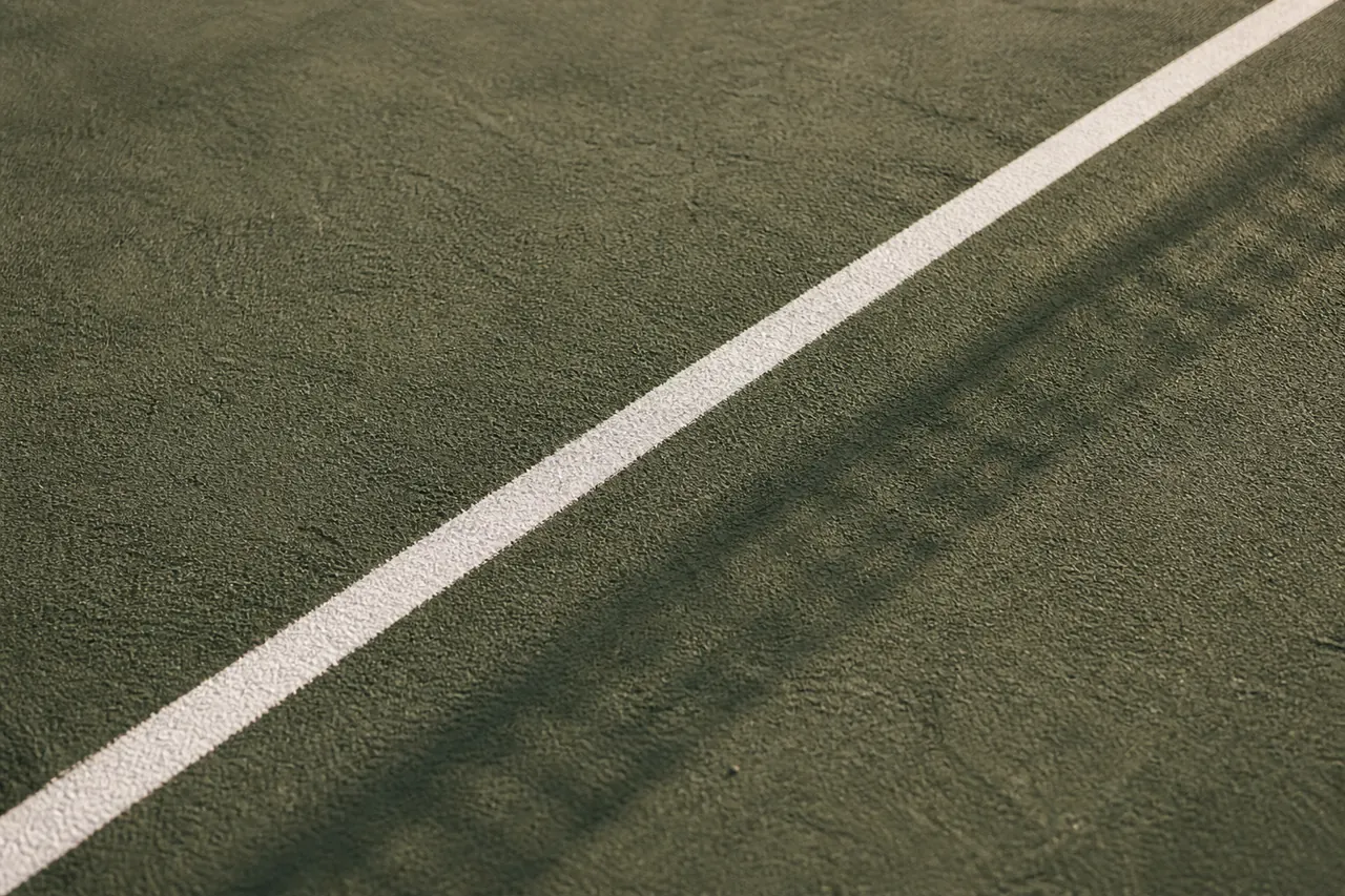 Close detail of a green court surface with a single straight white painted line